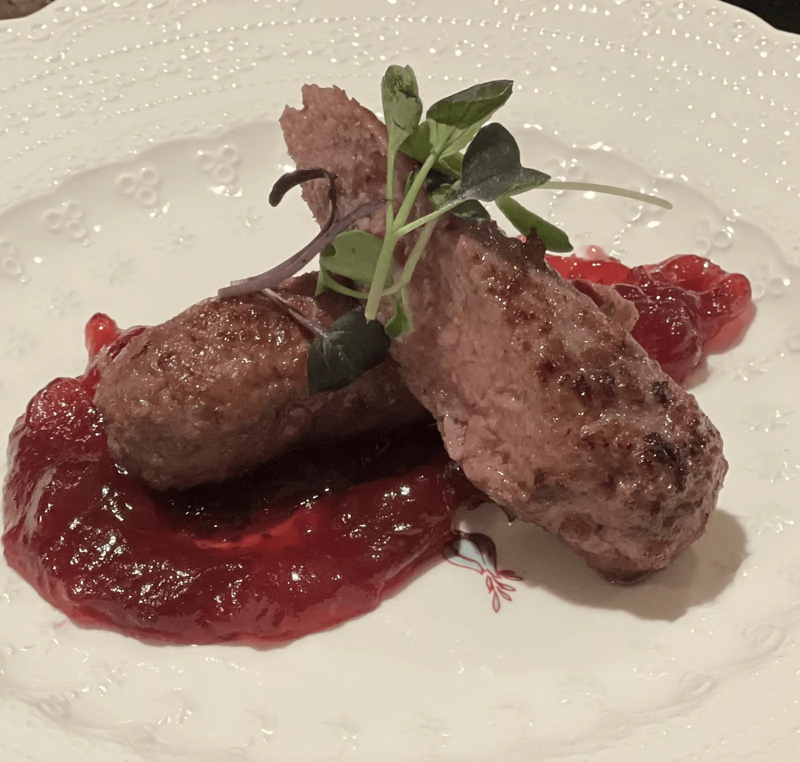 Duck and Armagnac sausage with red fruit sauce and microgreens.