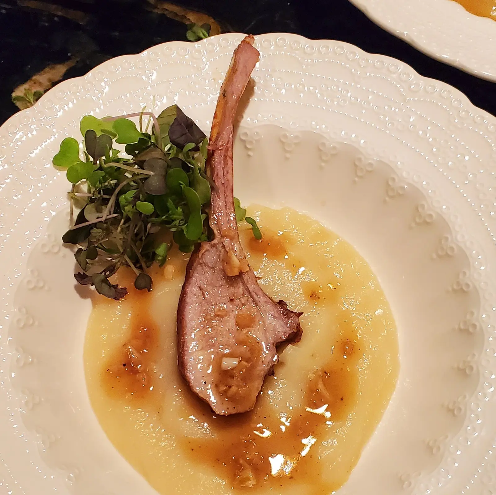 A wild boar rib chop served upright over puree and golden sauce.
