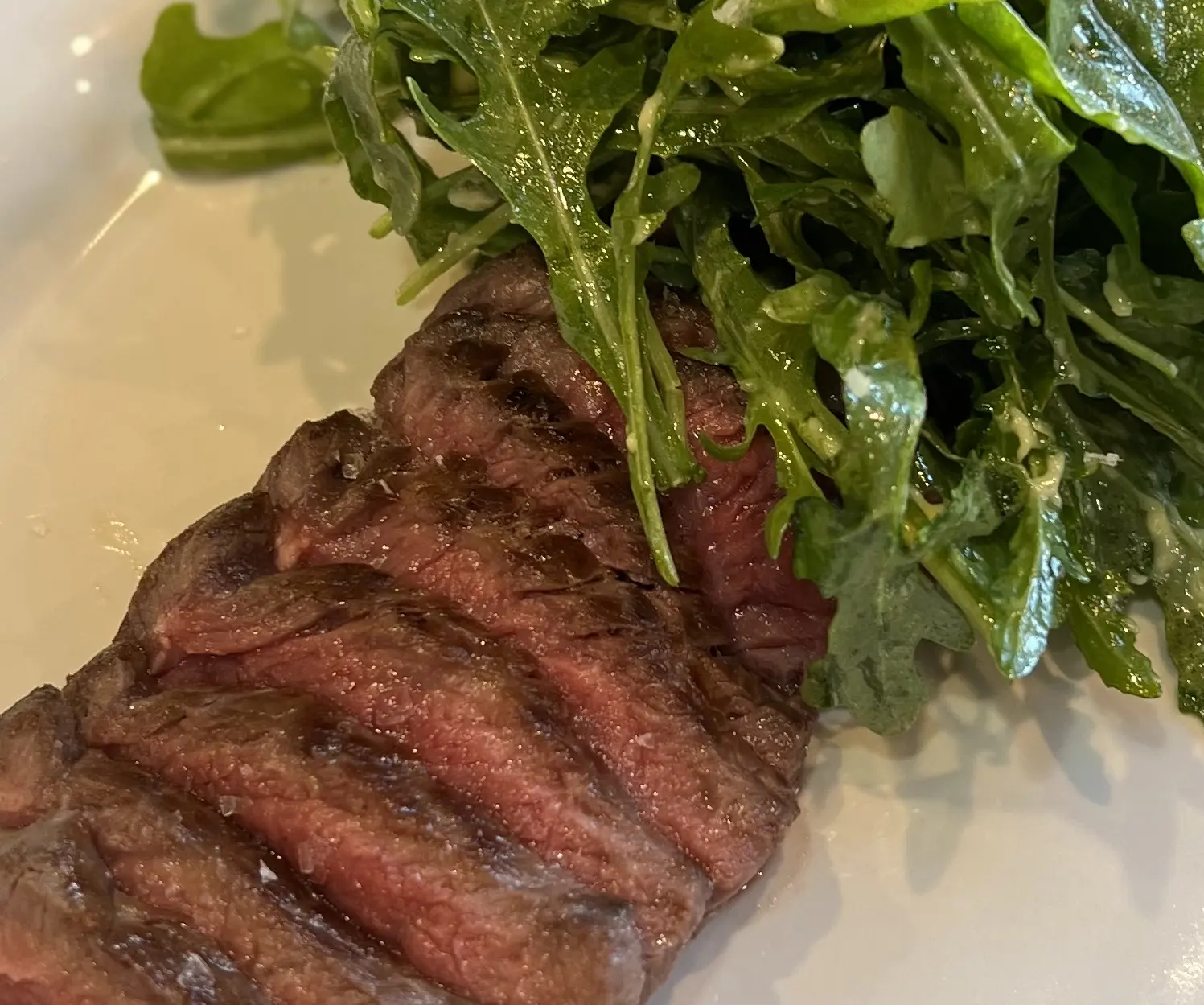 Sliced A5 Wagyu beef with a leafy green salad.