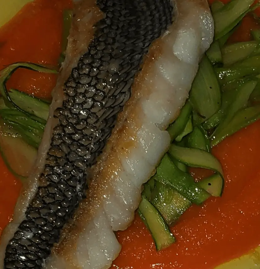 Crispy-skin sea bass over green vegetables and red sauce.