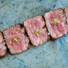 Three seared A5 Wagyu beef slices on a blue ceramic plate.