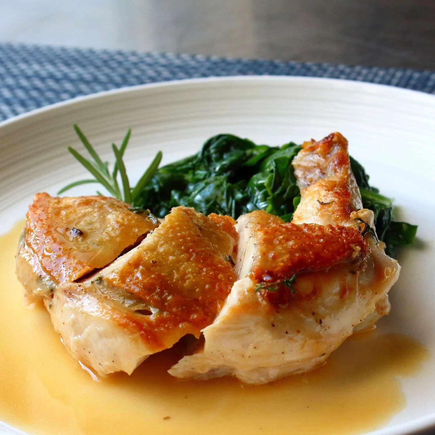 Golden roast chicken pieces with leafy greens and a light sauce.