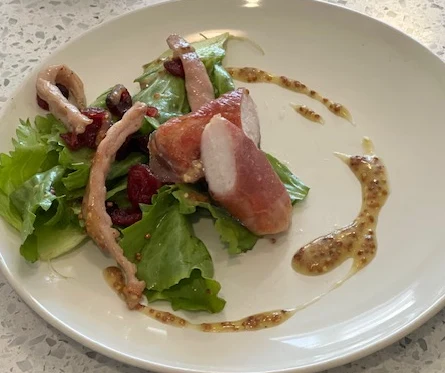 Rabbit loin with leafy greens, radishes and a grainy sauce.