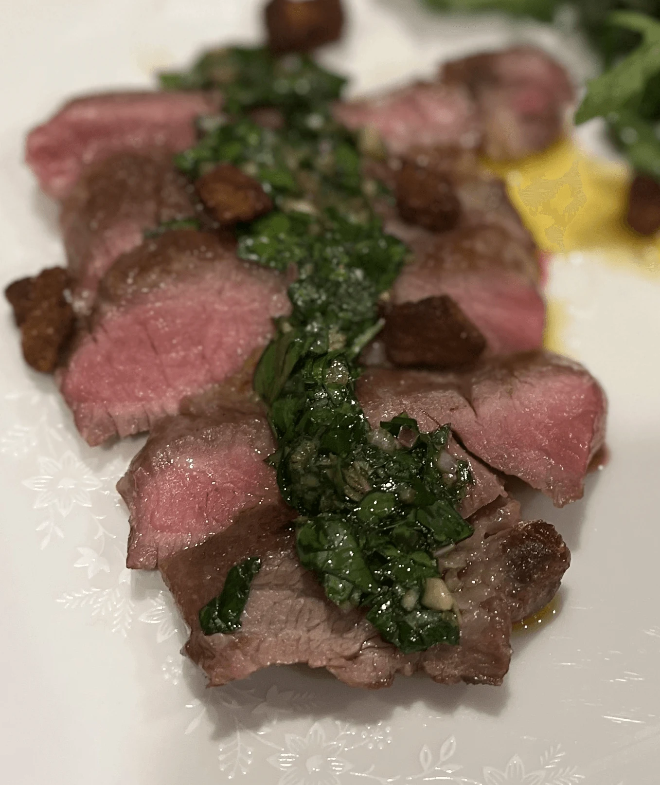 Sliced Iberico pluma with green herb sauce, puree and a leafy salad.