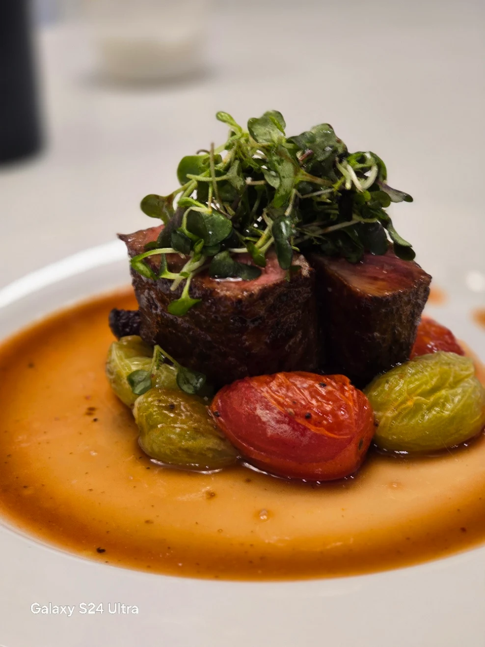 Beef medallions with roasted tomatoes, green vegetables and orange sauce.